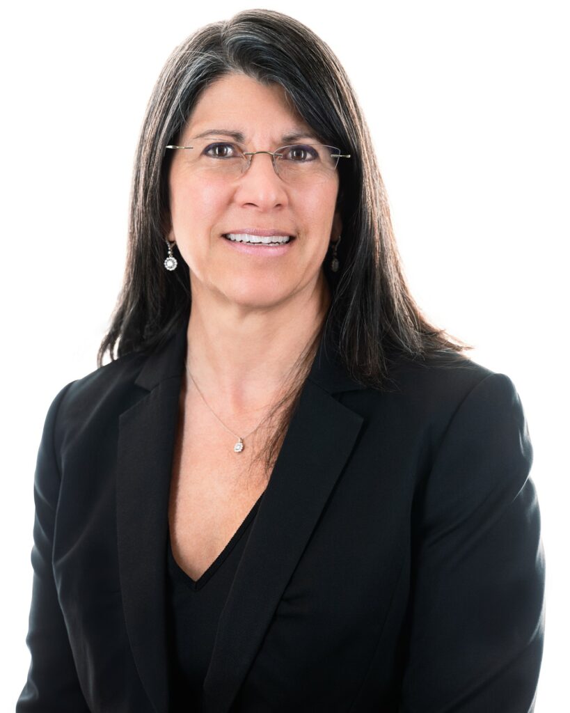 woman with glasses smiling in a blazer